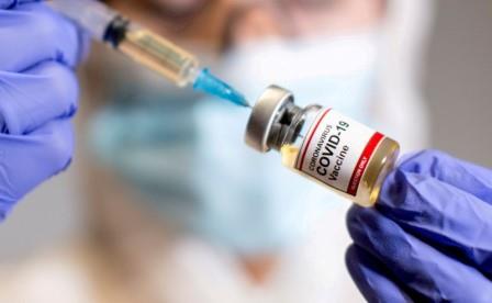 FILE PHOTO: A woman holds a small bottle labelled with a "Coronavirus COVID-19 Vaccine" sticker and a medical syringe in this illustration taken October 30, 2020. REUTERS/Dado Ruvic